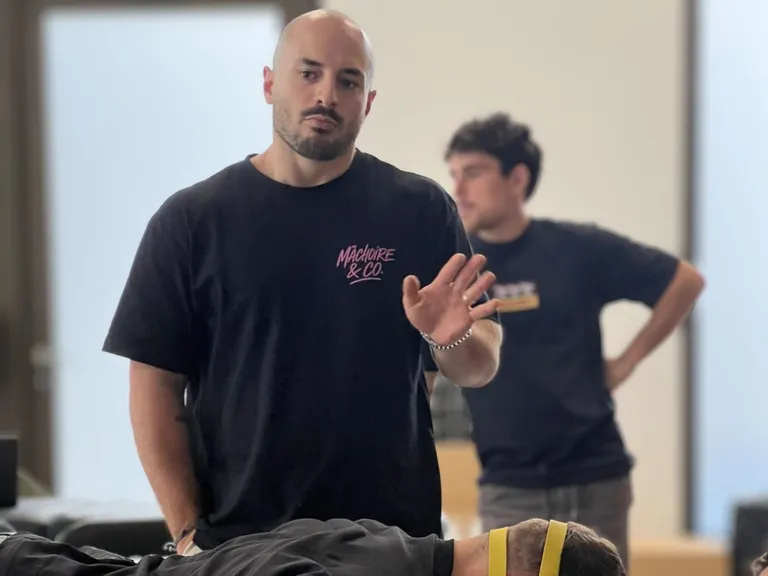 Quentin Hindelang encadre un exercice cervical en formation, patient allongé et bande élastique